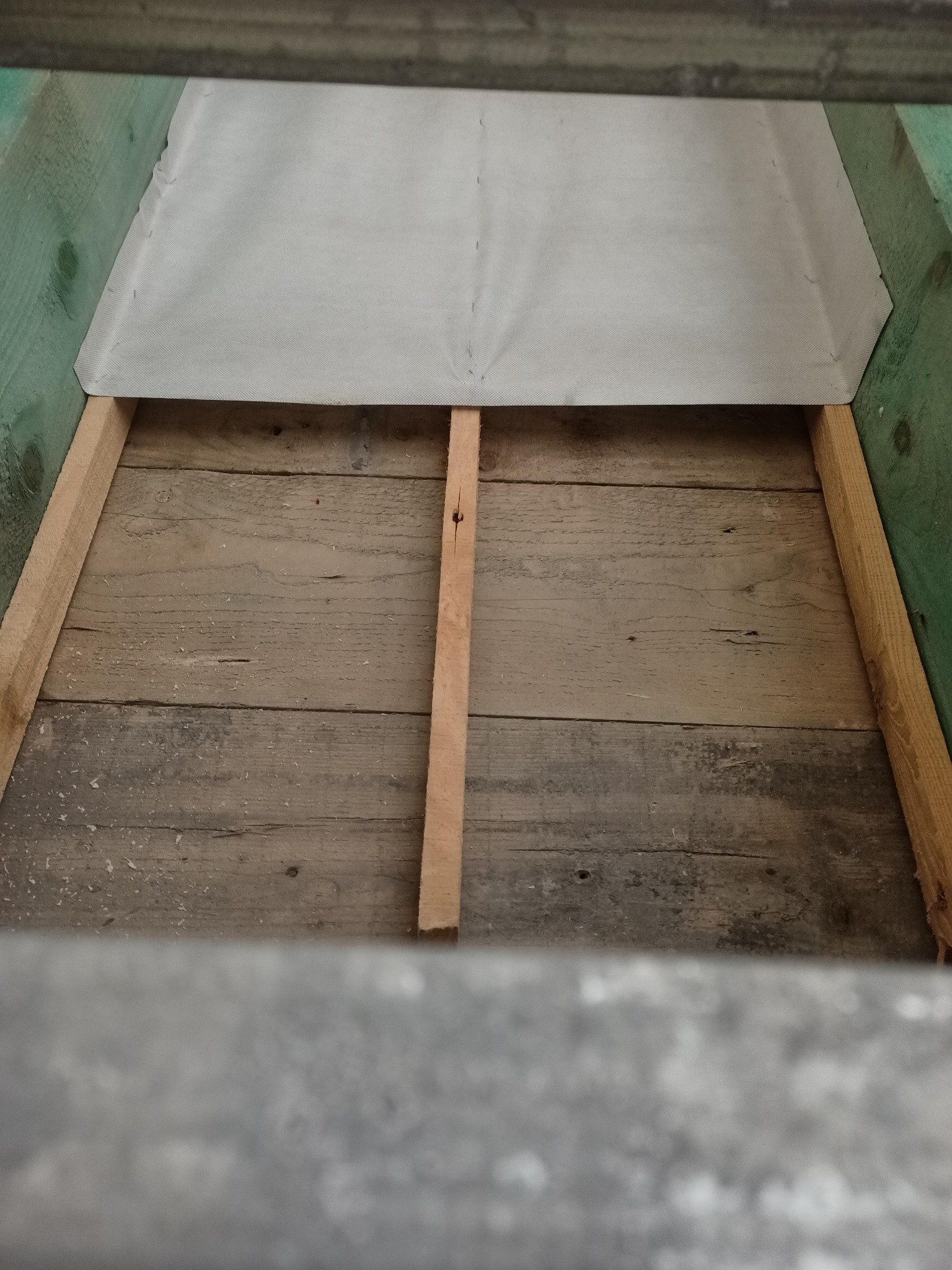 Przygotowanie podłoża: drewniana konstrukcja z deskami, zabezpieczona szarą membraną, gotowa do izolacji. Widok z góry.