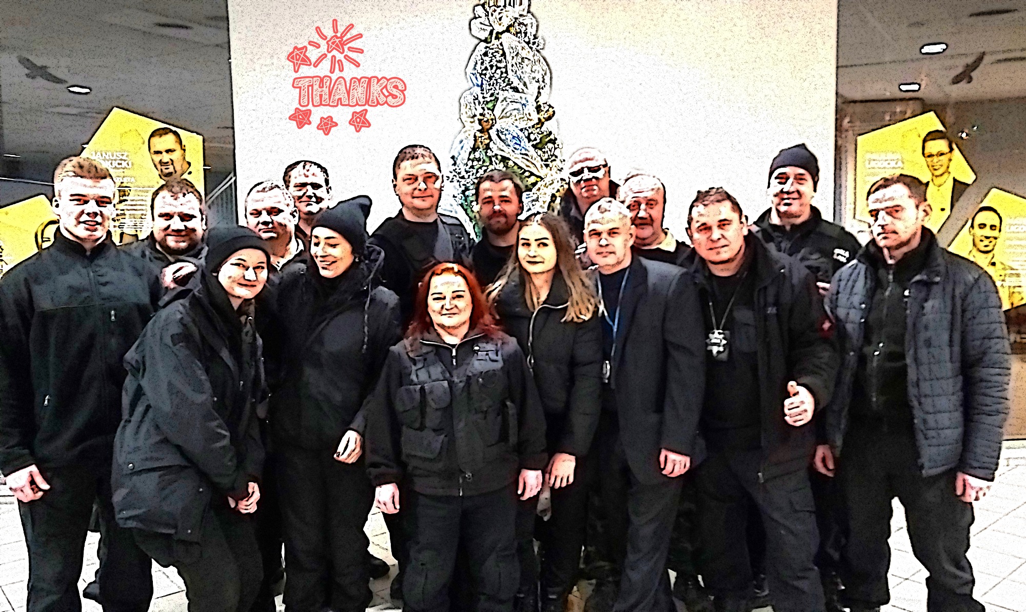 Grupa pracowników ochrony w Goleszowie pozuje do zdjęcia na tle ściany z dekoracjami świątecznymi i napisem 'Thanks'.