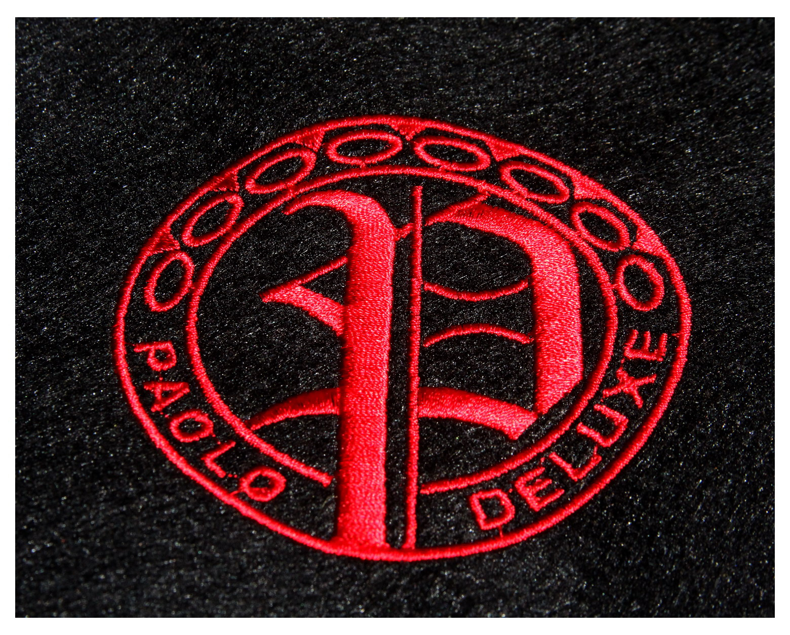 Czerwony, ozdobny haft logo 'Paolo Deluxe' na czarnym, teksturowanym materiale.