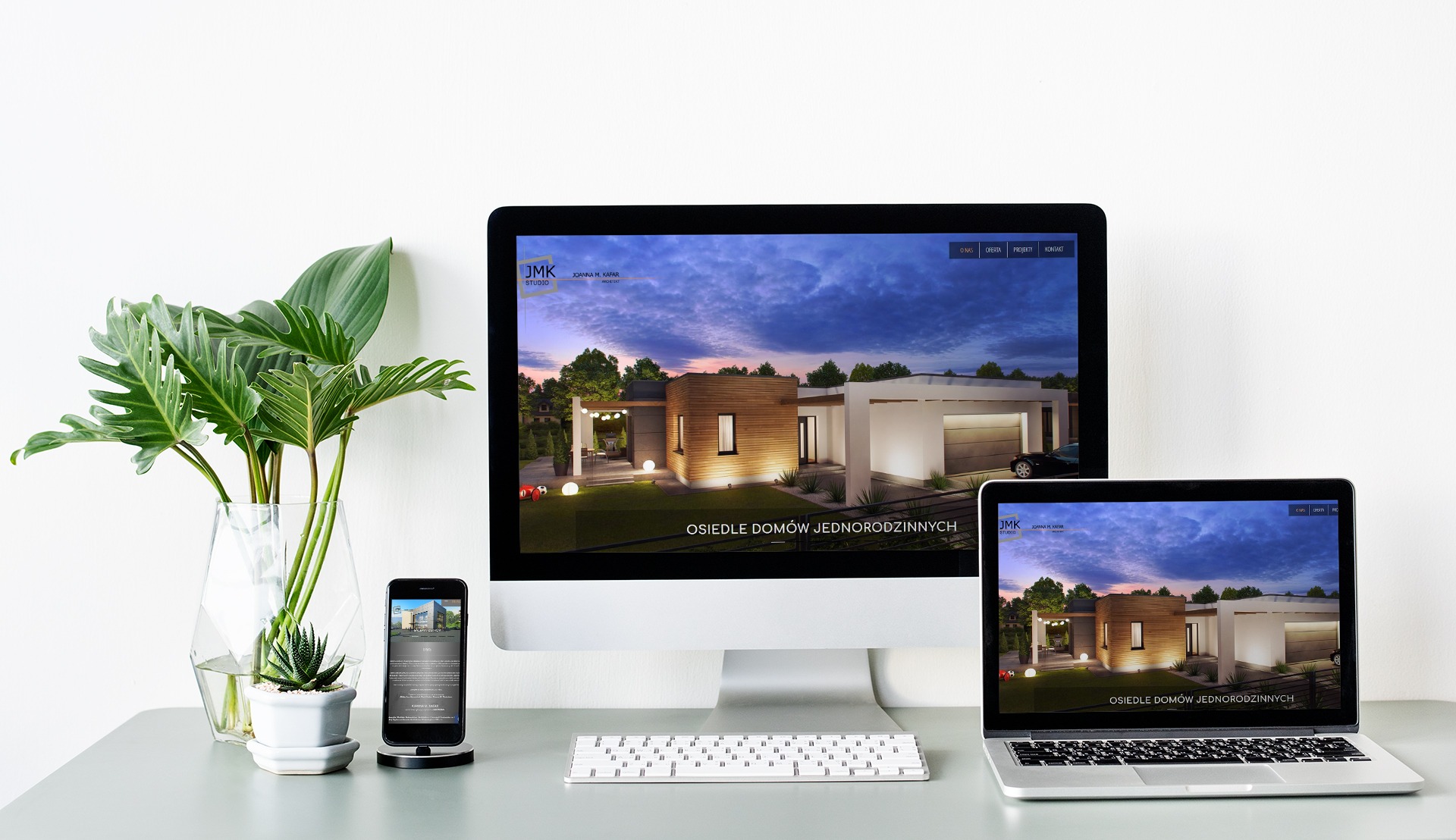 Wizualizacja osiedla domów jednorodzinnych na ekranach komputera, laptopa i smartfona, obok wazon z roślinami i sukulent w doniczce.