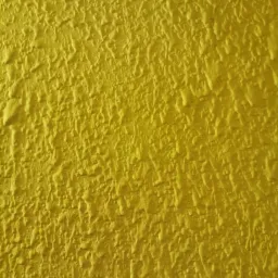 Żółta ściana pokryta grubą, nieregularną fakturą, przypominającą baranek.