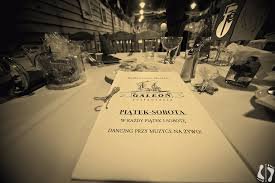 Uroczysty stół z menu restauracji Galeon, ustawiony na piątkowe i sobotnie wieczory z dancingiem i muzyką na żywo, w tle zastawa stołowa i dekoracje.