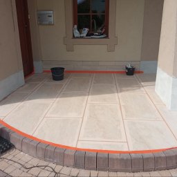 Tomasz - Wyłożony płytkami taras przed wejściem do domu, zabezpieczony pomarańczową taśmą malarską, widoczne dwa wiadra i zwinięty przedłużacz elektryczny.