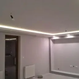 Pokój po remoncie z oświetleniem LED w suficie podwieszanym, świeżo pomalowane ściany na szaro z dekoracyjną ramą wnęki.