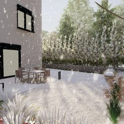 NIKO Biuro Architektury Krajobrazu - Zimowy ogród z nowoczesnym domem w tle, pokryty śniegiem. Widoczne krzewy, trawy ozdobne, stół z krzesłami i grill. Padający śnieg dodaje uroku.