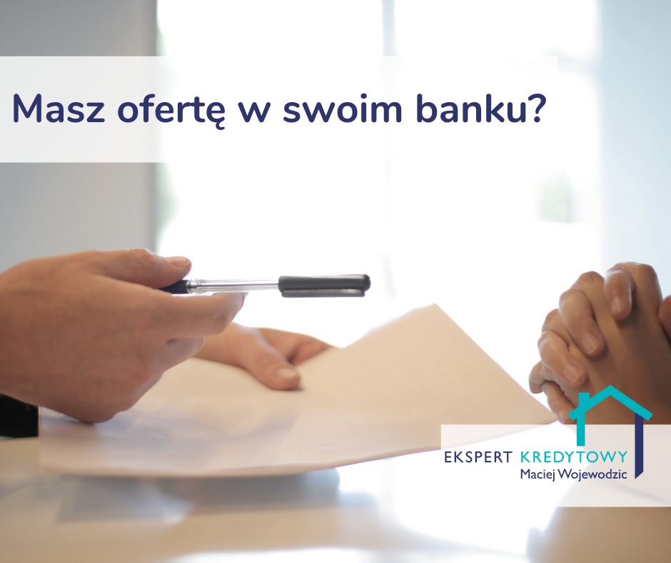 Osoba podaje dokument do podpisu długopisem, w tle złożone ręce, logo eksperta kredytowego w rogu.