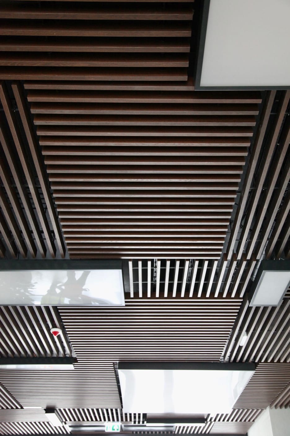 Sufit podwieszany z drewnianych listew i wbudowanym oświetleniem LED, widok z dołu.