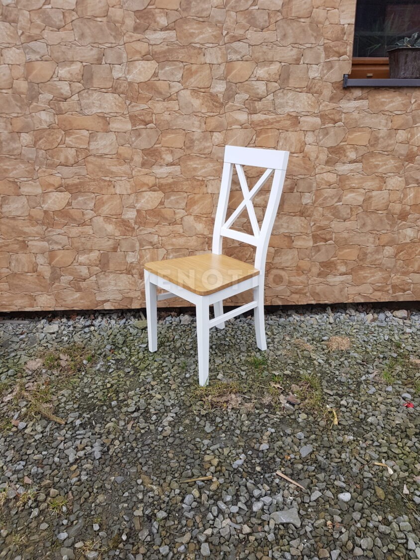 Białe krzesło z drewnianym siedziskiem w stylu rustykalnym na tle kamiennej ściany i żwirowego podłoża.