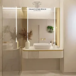 Elegancka łazienka w odcieniach bieli i beżu z podświetlanym lustrem, owalną umywalką nablatową, dekoracyjną trawą pampasową w wazonie i wiszącą rośliną doniczkową, widoczna kabina prysznicowa.