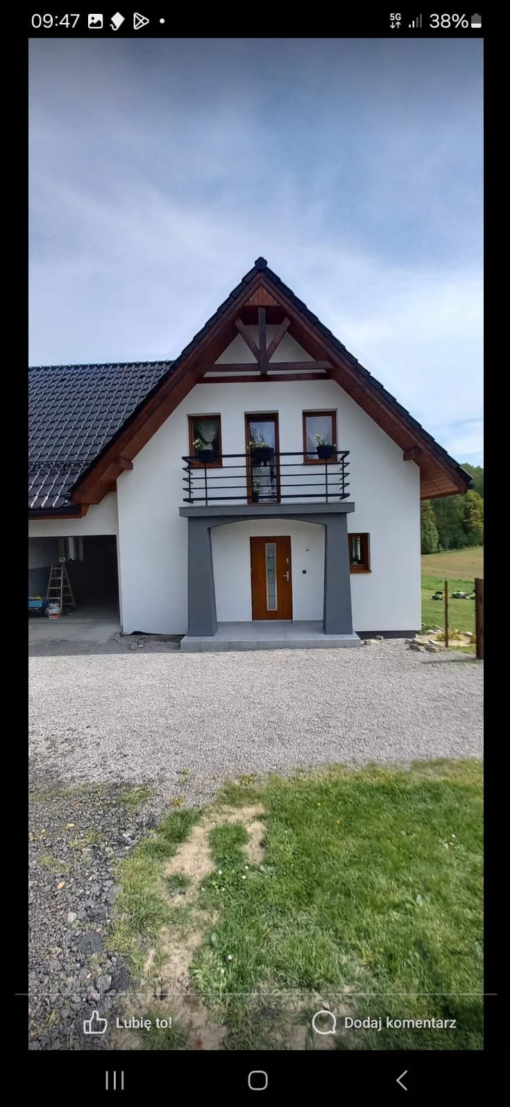 Nowoczesny dom jednorodzinny z balkonem, biała elewacja, grafitowe akcenty, czarny dach, widok z zewnątrz na podjazd z kamienia i trawnik, drabina w garażu.