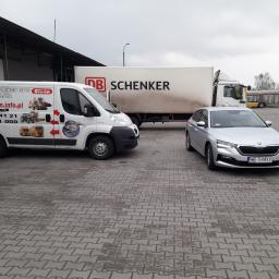 P.P.H.U. SYSTEM - Flota pojazdów na szarym brukowanym placu: biała furgonetka z grafiką systemów monitoringu GPS i kontroli paliwa, ciężarówka DB Schenker i srebrna Skoda z tablicą rejestracyjną WE 544XV.