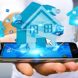 Dłoń trzyma smartfon z wyświetlanym modelem 3D domu, kluczy i ikon aplikacji, symbolizujących zarządzanie domem za pomocą technologii.