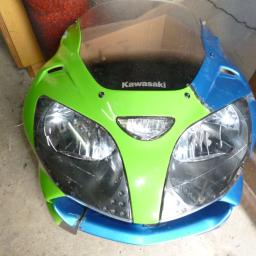 Foto Wideo Usługi - Spawanie Plastików - Przedni owiewka motocykla Kawasaki, pomalowana na zielono i niebiesko, z widocznymi śladami użytkowania i drobnymi uszkodzeniami lakieru.