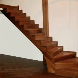 Schody z drewna egzotycznego z zakrętem, dopasowane do podłogi z parkietu w ciepłym odcieniu brązu, widoczne w jasnym wnętrzu.