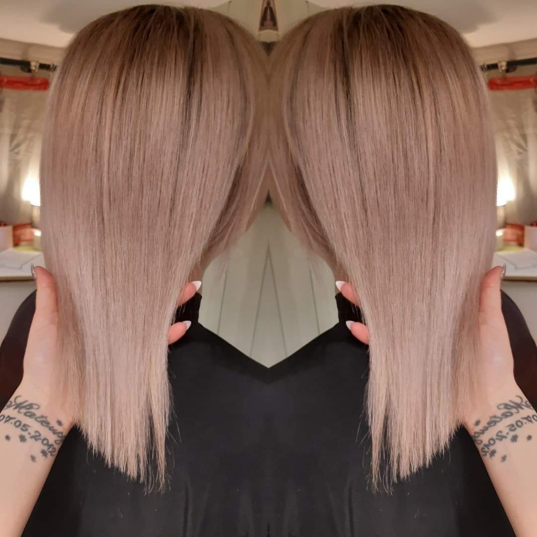 Proste, popielate włosy po koloryzacji, widoczne dłonie modelki z tatuażami na nadgarstkach, białe paznokcie, lustrzane odbicie.