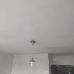 Przygotowanie do malowania: sufit i ściany po szpachlowaniu, zabezpieczona lampa wisząca, zakryte folią drzwi.