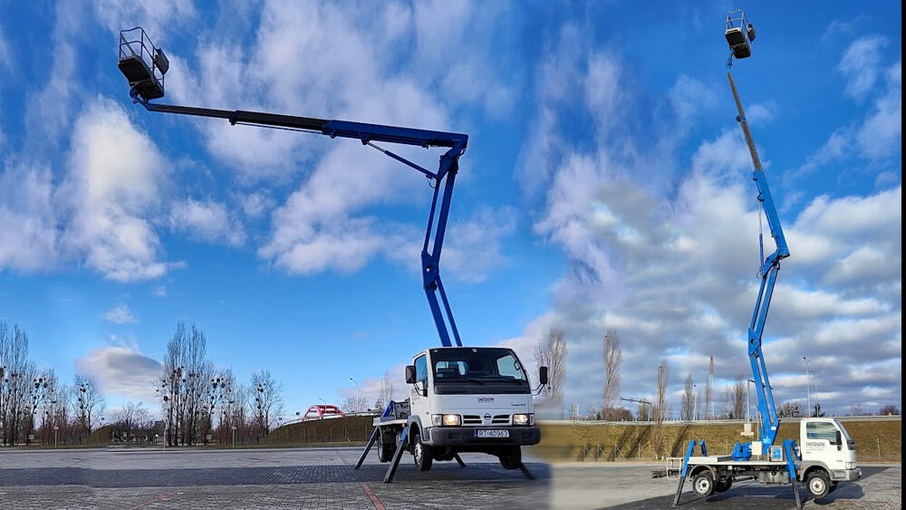 Dwie platformy robocze na wysięgnikach teleskopowych, umieszczone na podwoziach samochodowych, stoją na placu pod błękitnym, lekko pochmurnym niebem.