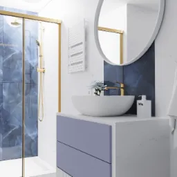 Nowoczesna łazienka z kabiną prysznicową w niebieskie wzory, białą umywalką nablatową na fioletowej szafce, okrągłym lustrem i złotymi akcentami.