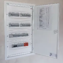 Otwarta, biała skrzynka rozdzielcza ETI z bezpiecznikami i listą zabezpieczeń, zamontowana na jasnej ścianie. Widoczne oznaczenia numerów i typów wyłączników.