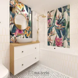 Jasna łazienka z akcentami tropikalnymi: białe płytki ułożone pionowo z żółtymi fugami, wzorzysta tapeta z motywem kwiatów i ptaków, okrągłe lustro nad białą szafką z drewnianym blatem i umywalką...