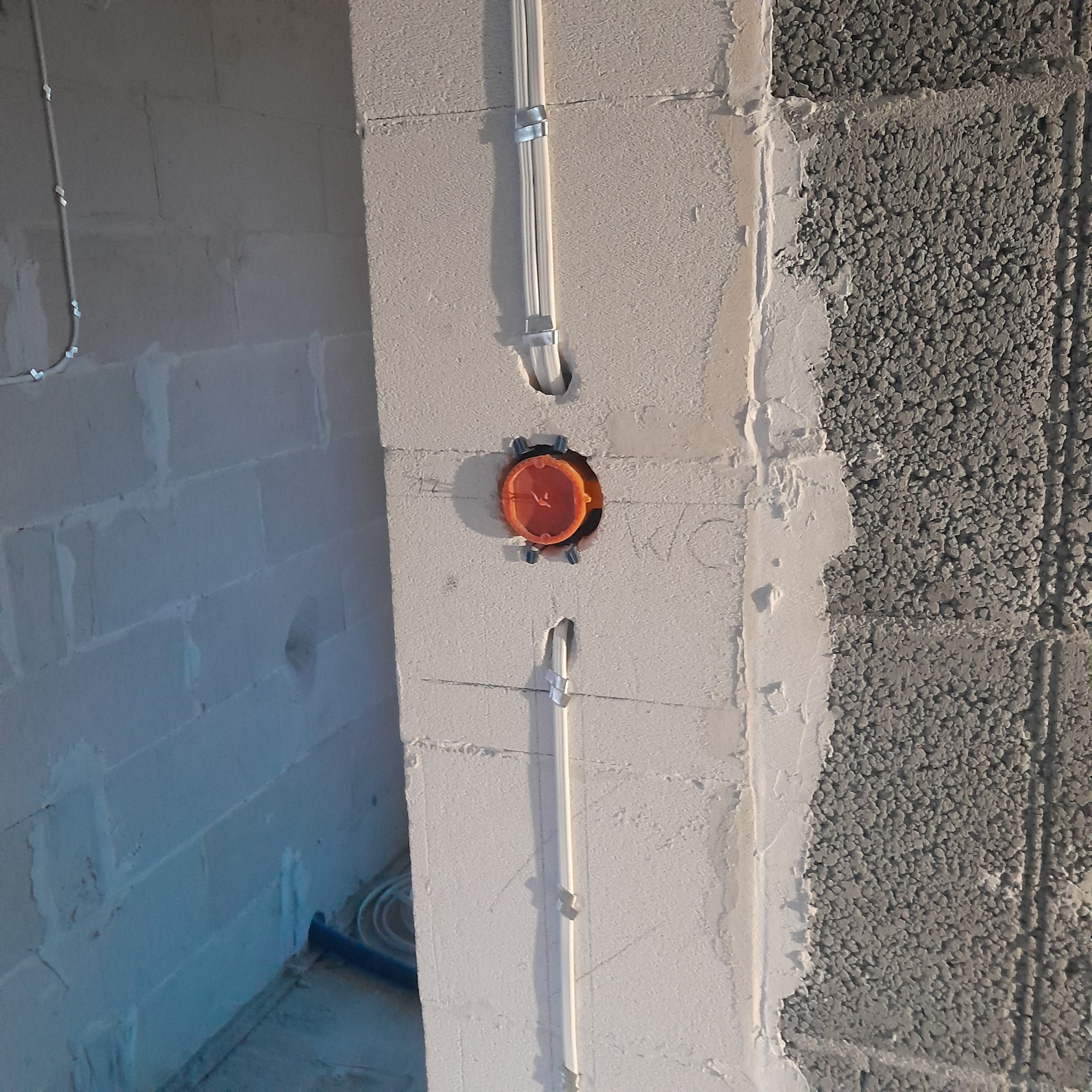 Wewnętrzna instalacja: przewody w peszlach mocowane do ściany z betonu komórkowego, puszka elektryczna wmurowana w ścianę. Etap prac przed tynkowaniem.