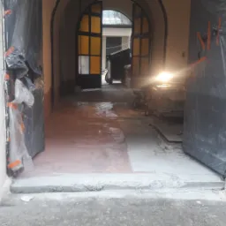 Przygotowanie podłoża pod posadzkę wewnątrz budynku, z widocznym fragmentem wylewki samopoziomującej i zabezpieczonymi folią drzwiami.