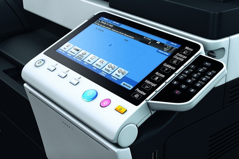 Panel sterowania nowoczesnej kserokopiarki z dotykowym ekranem i wysuwaną klawiaturą numeryczną, widoczne ikony funkcji i ustawień.