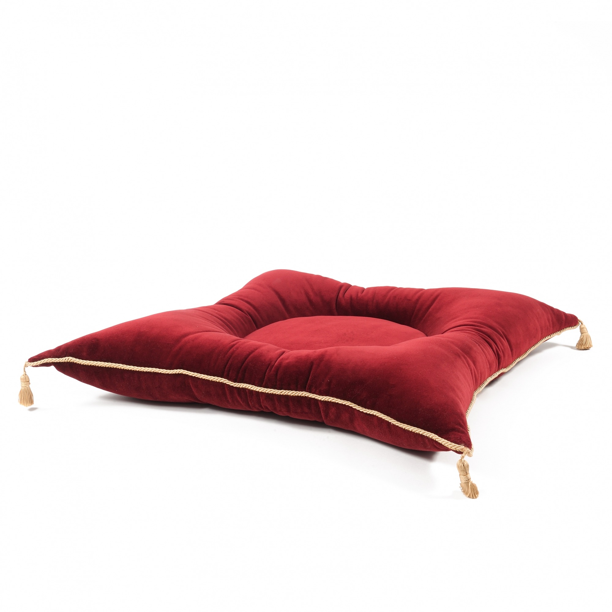 Czerwona, kwadratowa poduszka z weluru z ozdobnymi sznurami i frędzlami w rogach, leżąca na białym tle.