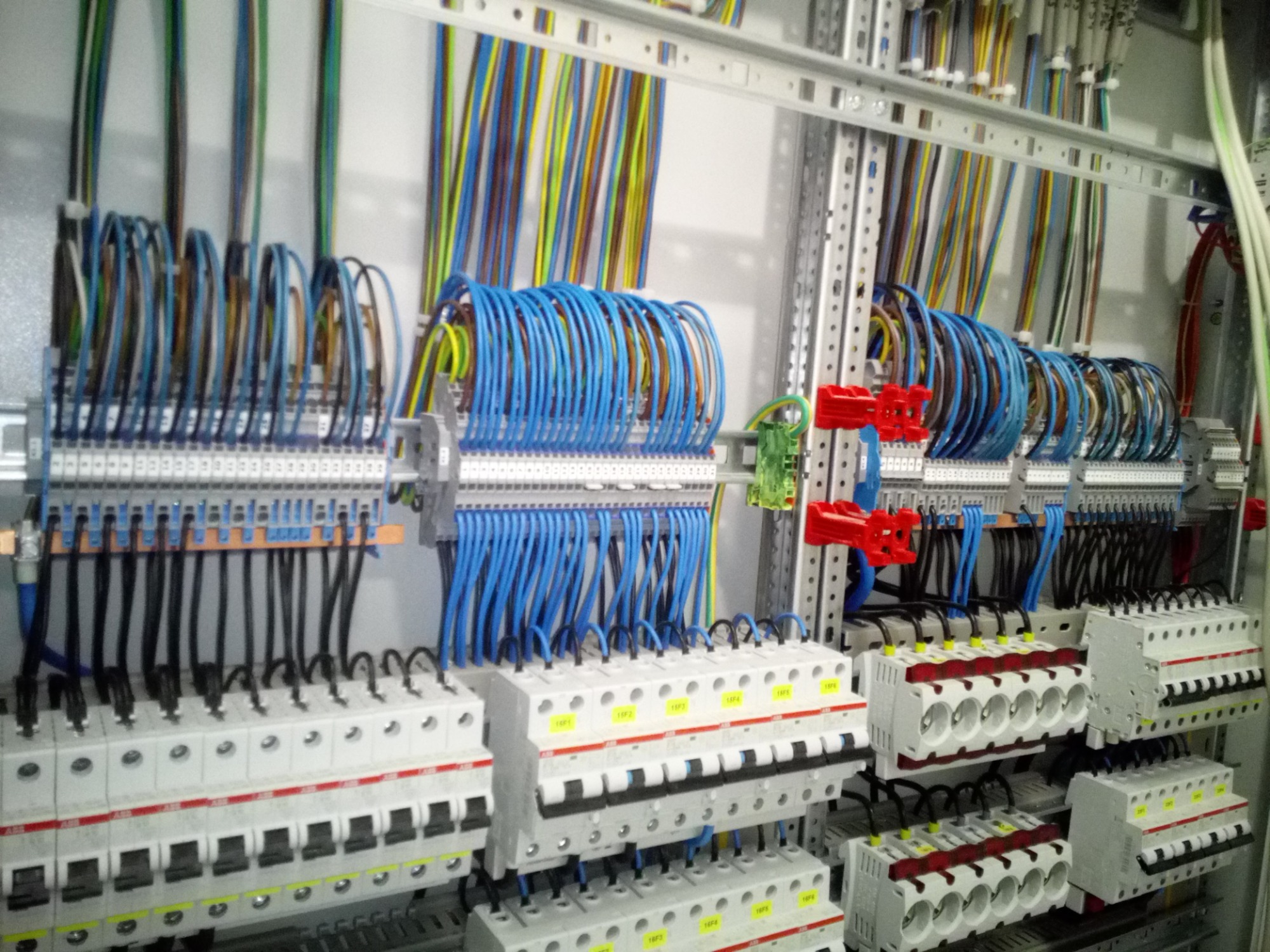 Rozdzielnica elektryczna z licznymi przewodami w różnych kolorach, zamontowana w Skarżysku-Kamiennej. Widoczne zabezpieczenia i listwy zaciskowe.