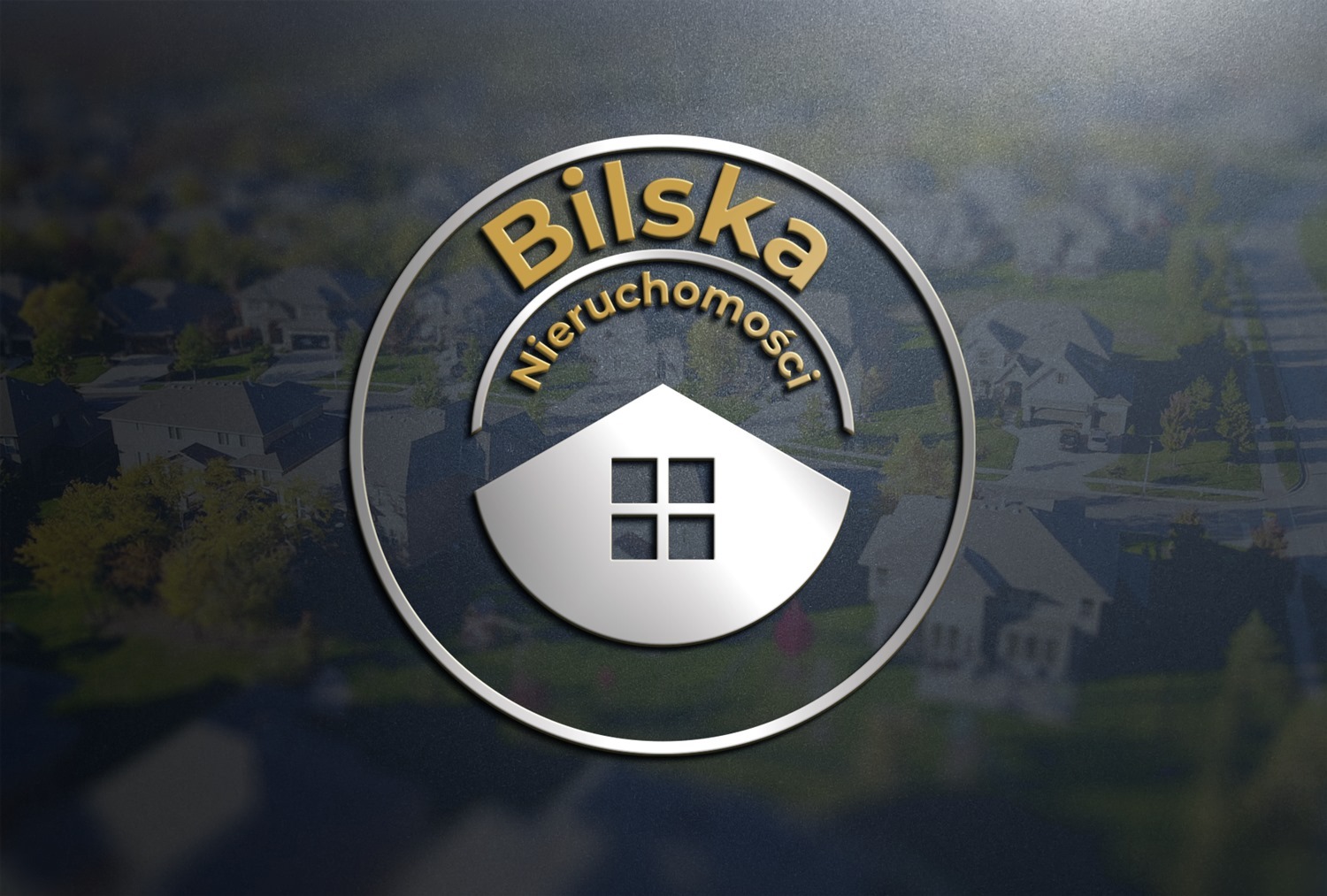 Logo firmy Bilska Nieruchomości: złoty napis w okręgu, poniżej biały symbol domu z czterema oknami, w tle rozmyty widok osiedla domków jednorodzinnych.