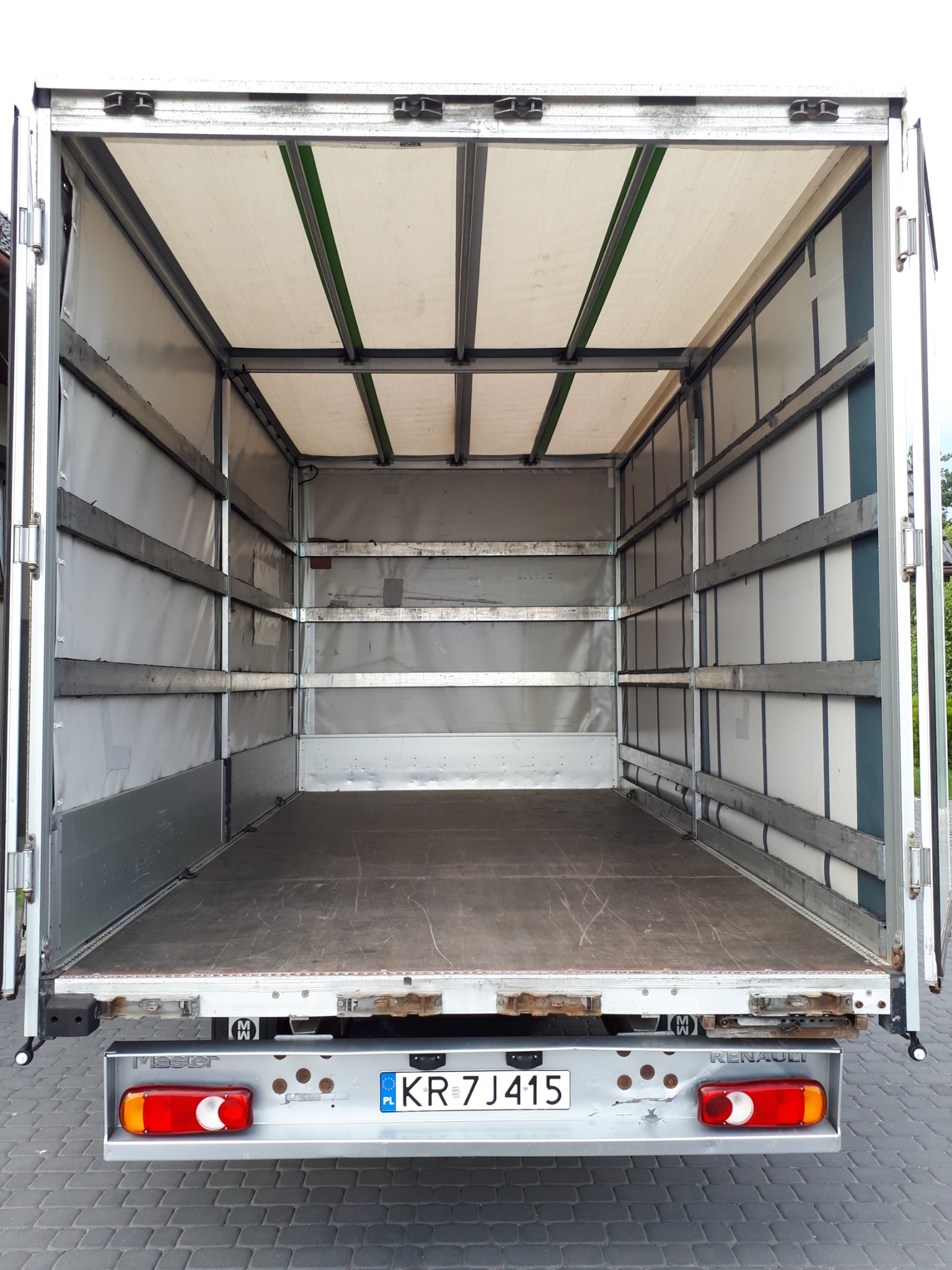 Wnętrze pustej przestrzeni ładunkowej samochodu dostawczego Renault Master z otwartymi drzwiami, gotowego do załadunku w Sieprawiu. Widoczna tablica rejestracyjna KR 7J415.