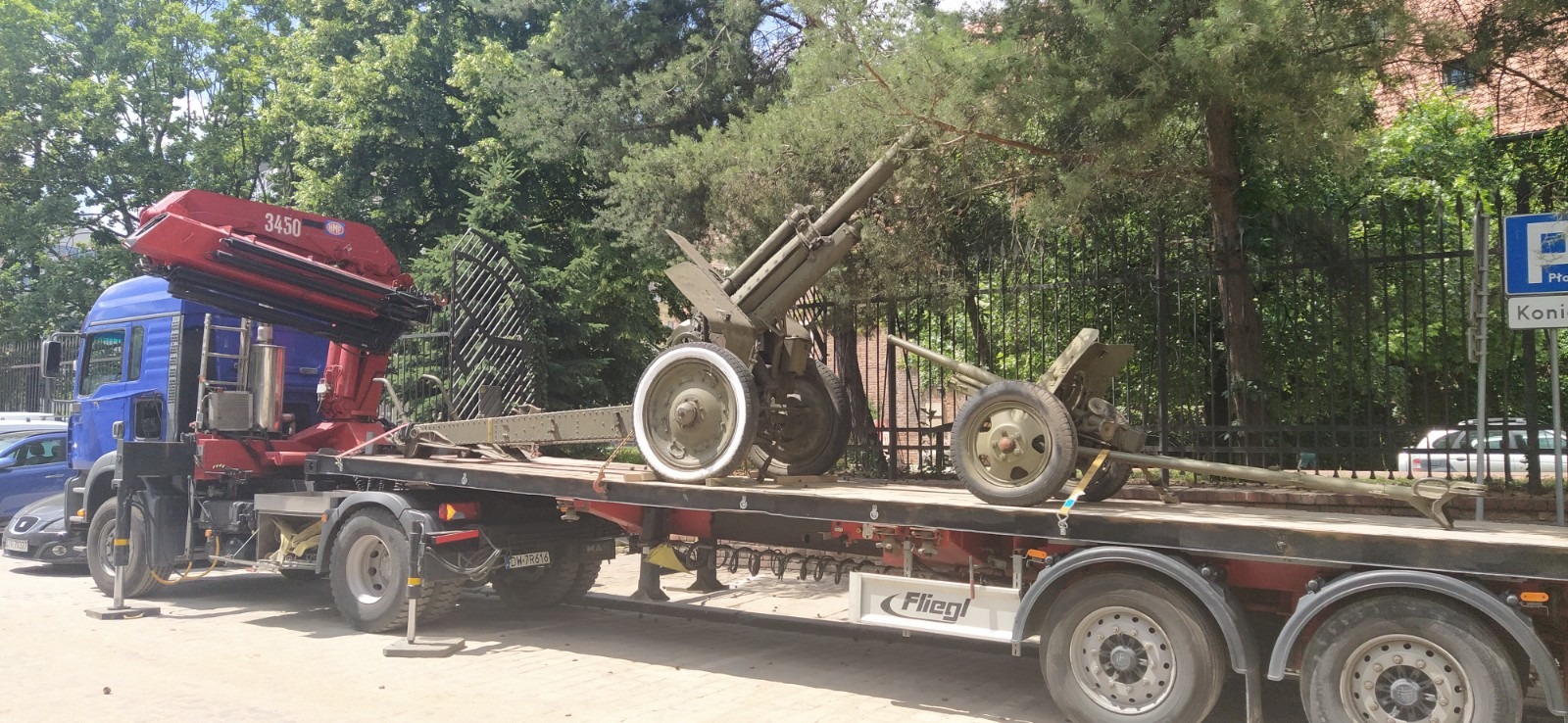 Dwa działa przeciwlotnicze na naczepie ciężarówki z żurawiem HMF 3450, zabezpieczone pasami transportowymi.
