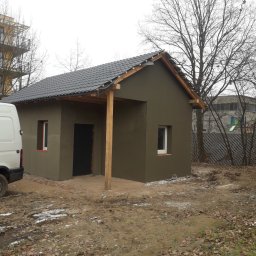 M&S usługi wykończeniowo/budowlane - Budynek po nałożeniu surowej, ciemnej elewacji we Wrocławiu, widoczny fragment białego busa i teren z resztkami śniegu.