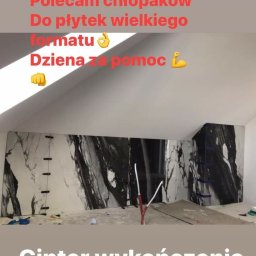 M&S usługi wykończeniowo/budowlane - Układanie wielkoformatowych płytek imitujących marmur na ścianie pod skosem, widoczne przyssawki montażowe i narzędzia.