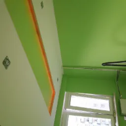 Świeżo pomalowane na zielono wnętrze z podwieszanym sufitem z oświetleniem LED, widoczne okno i rury od odkurzacza na suficie.