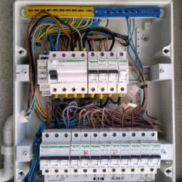 Otwarta skrzynka elektryczna z bezpiecznikami i okablowaniem w Gardei, widoczne elementy marki Schneider Electric i Eaton.