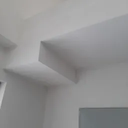 Białe ściany i sufit z nietypową konstrukcją architektoniczną, świeżo po malowaniu, z widoczną fakturą powierzchni.