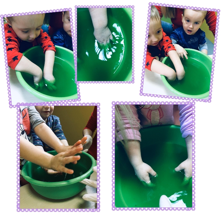 Dzieci bawią się zieloną cieczą w misce, eksperyment sensoryczny z udziałem opiekuna.