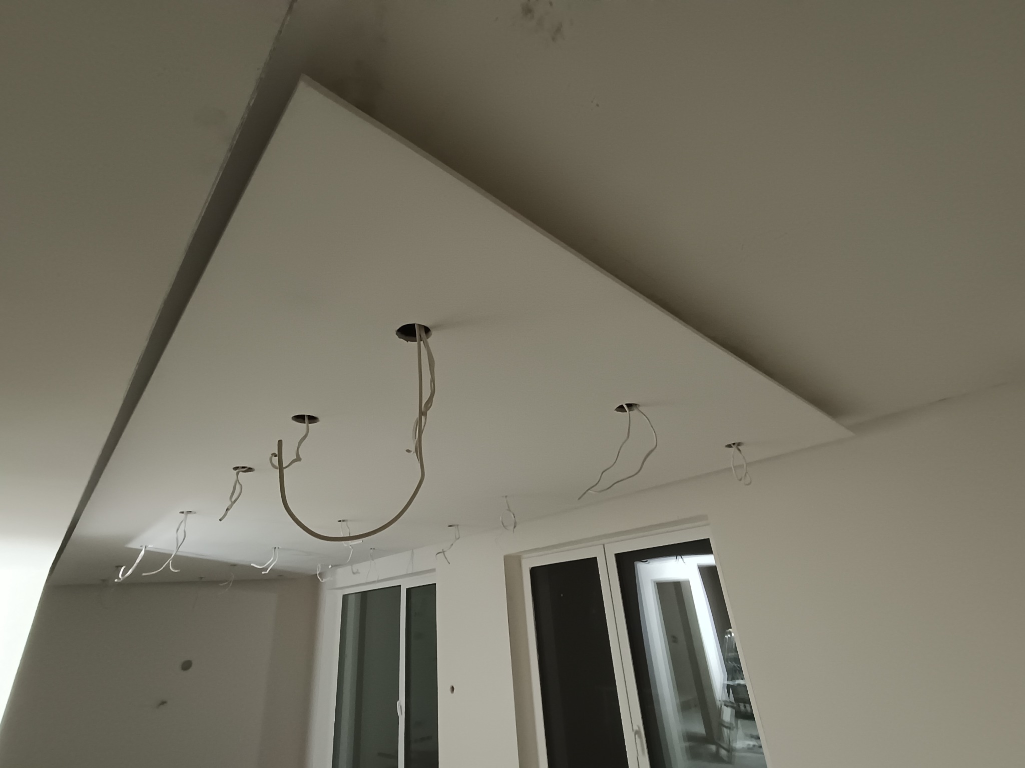 Wykończony fragment sufitu podwieszanego z płyt karton-gips z widocznymi przewodami elektrycznymi, przygotowany do dalszych prac wykończeniowych.