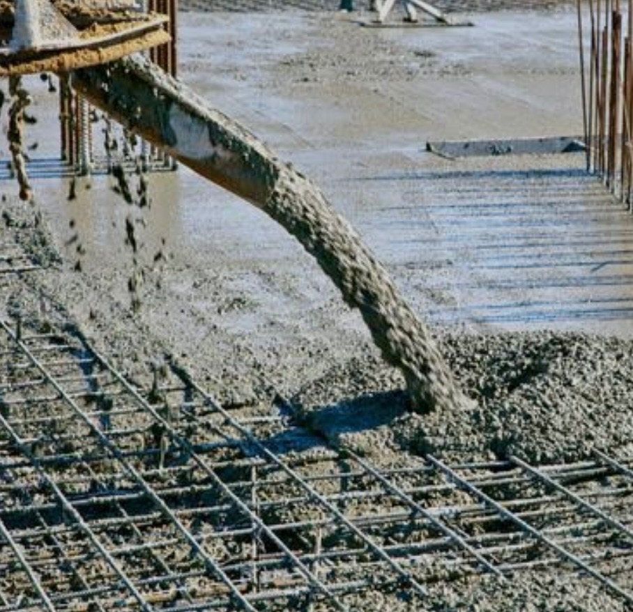 Wylewanie betonu na siatkę zbrojeniową. Widoczne pręty zbrojeniowe i świeży beton. Ujęcie z góry, ukazujące proces betonowania fundamentów.