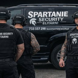 SPARTANIE-SECURITY Barbara Packiewicz - Trzech ochroniarzy w czarnych uniformach stoi przed czarnym SUV-em z logo i danymi kontaktowymi. Widoczne tatuaże na rękach jednego z mężczyzn. Ujęcie od pasa w górę.