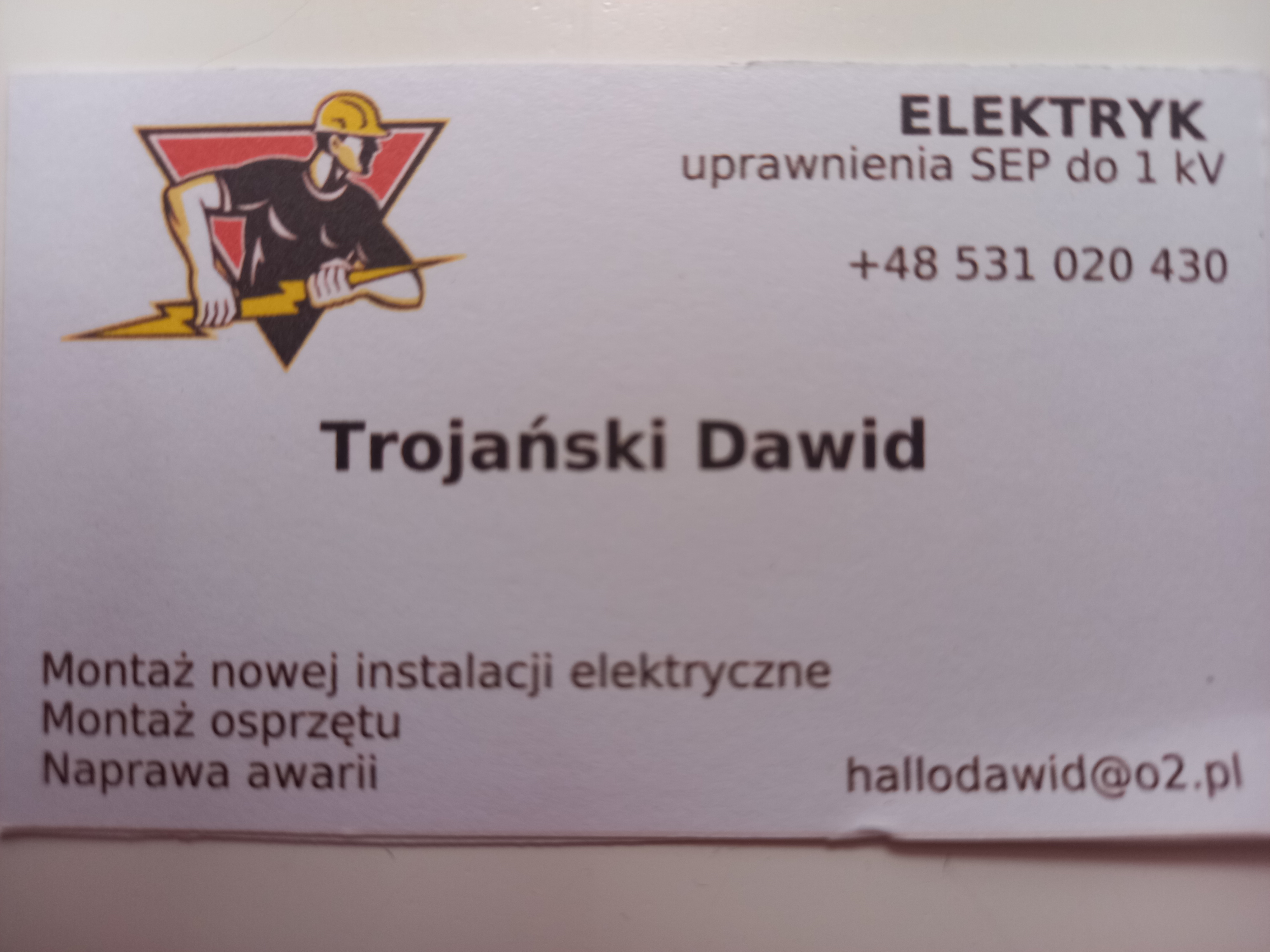 Wizytówka firmy elektrycznej: logo z elektrykiem trzymającym błyskawicę, dane kontaktowe, uprawnienia SEP, zakres usług: montaż instalacji, montaż osprzętu, naprawa awarii.