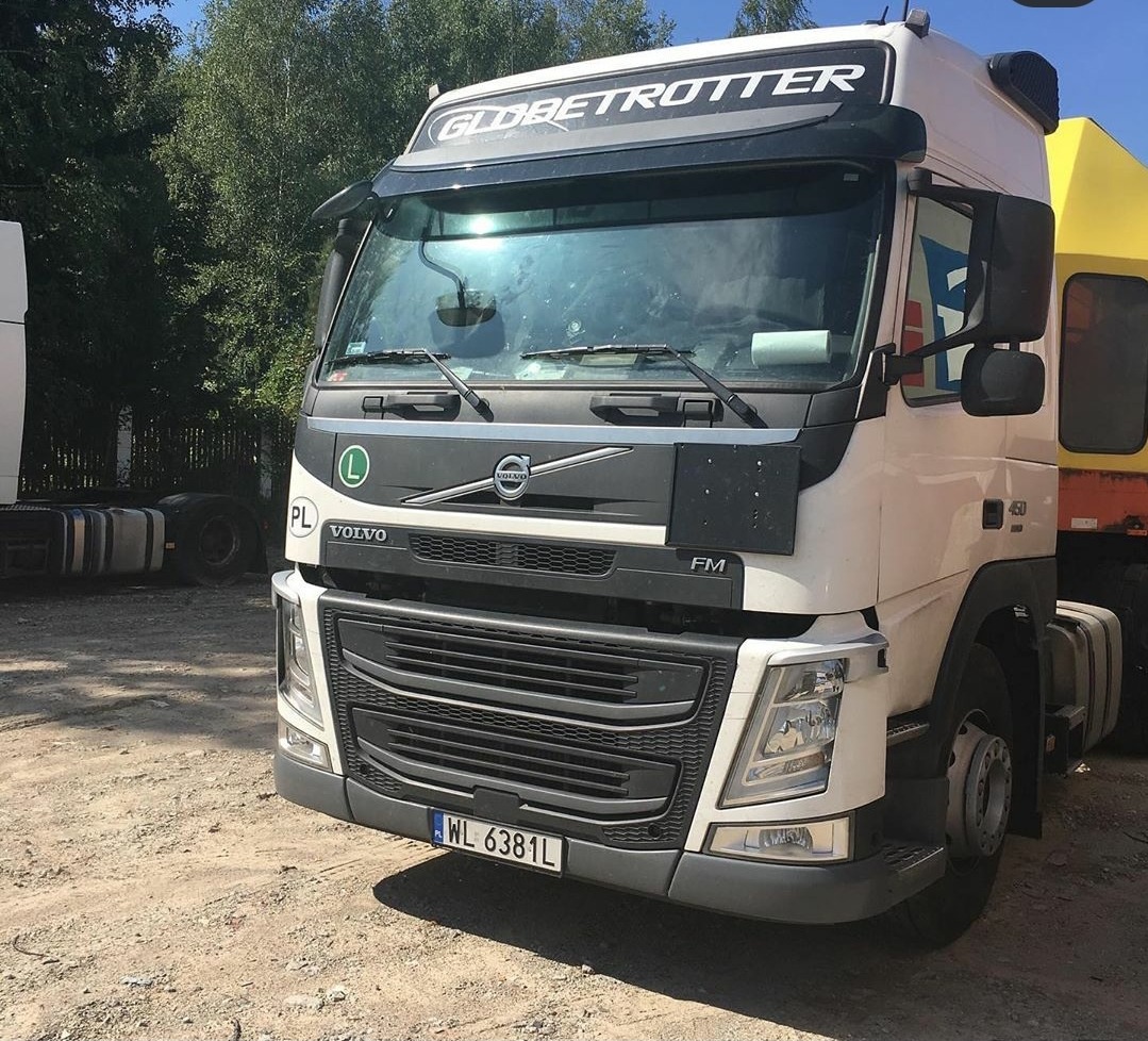 Biała ciężarówka Volvo Globetrotter z polską rejestracją WL 6381L, zaparkowana na szutrowym placu, widoczna z przodu pod kątem.