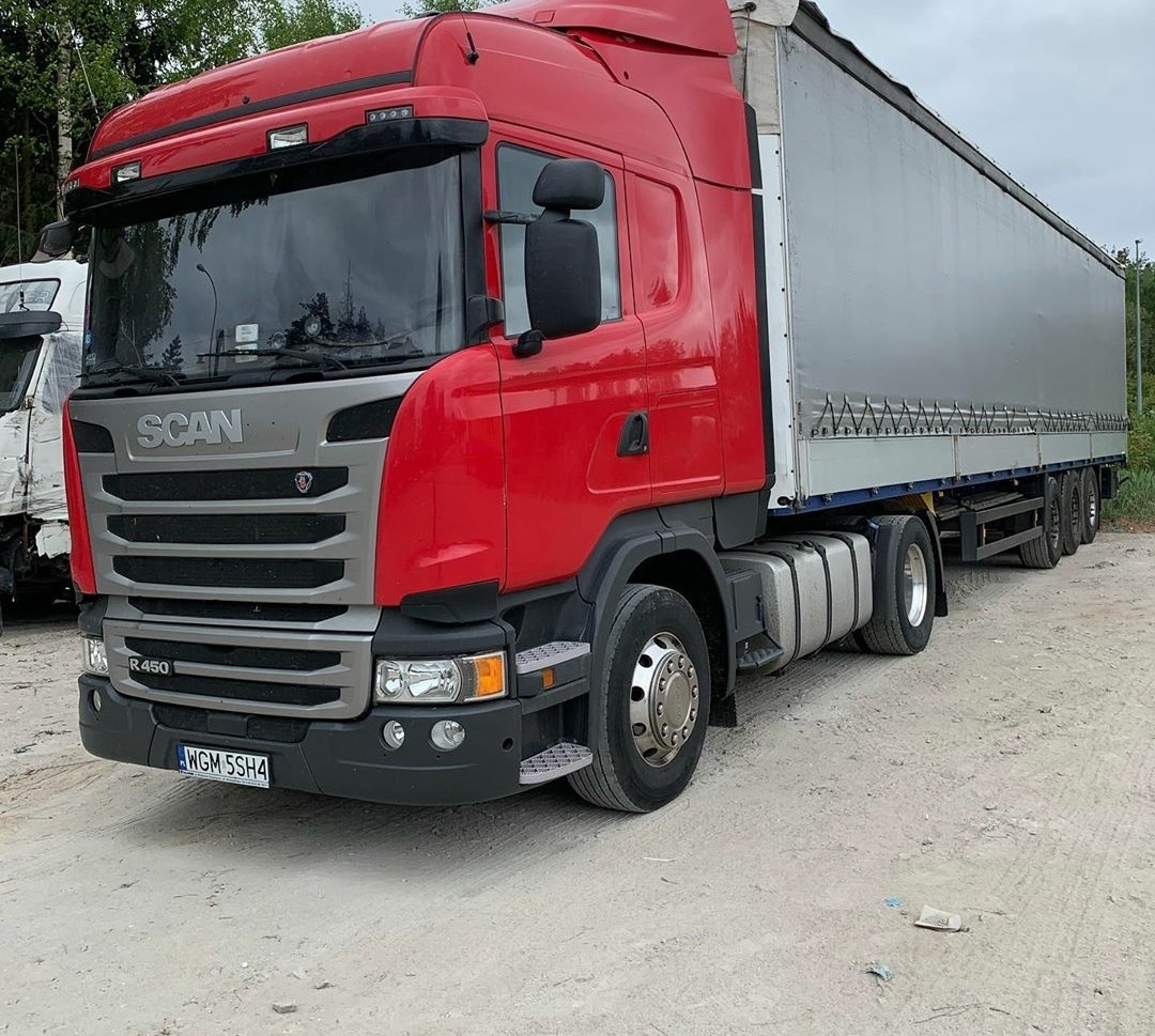 Czerwona ciężarówka Scania R450 z naczepą na placu, widoczna tablica rejestracyjna WGM 5SH4.