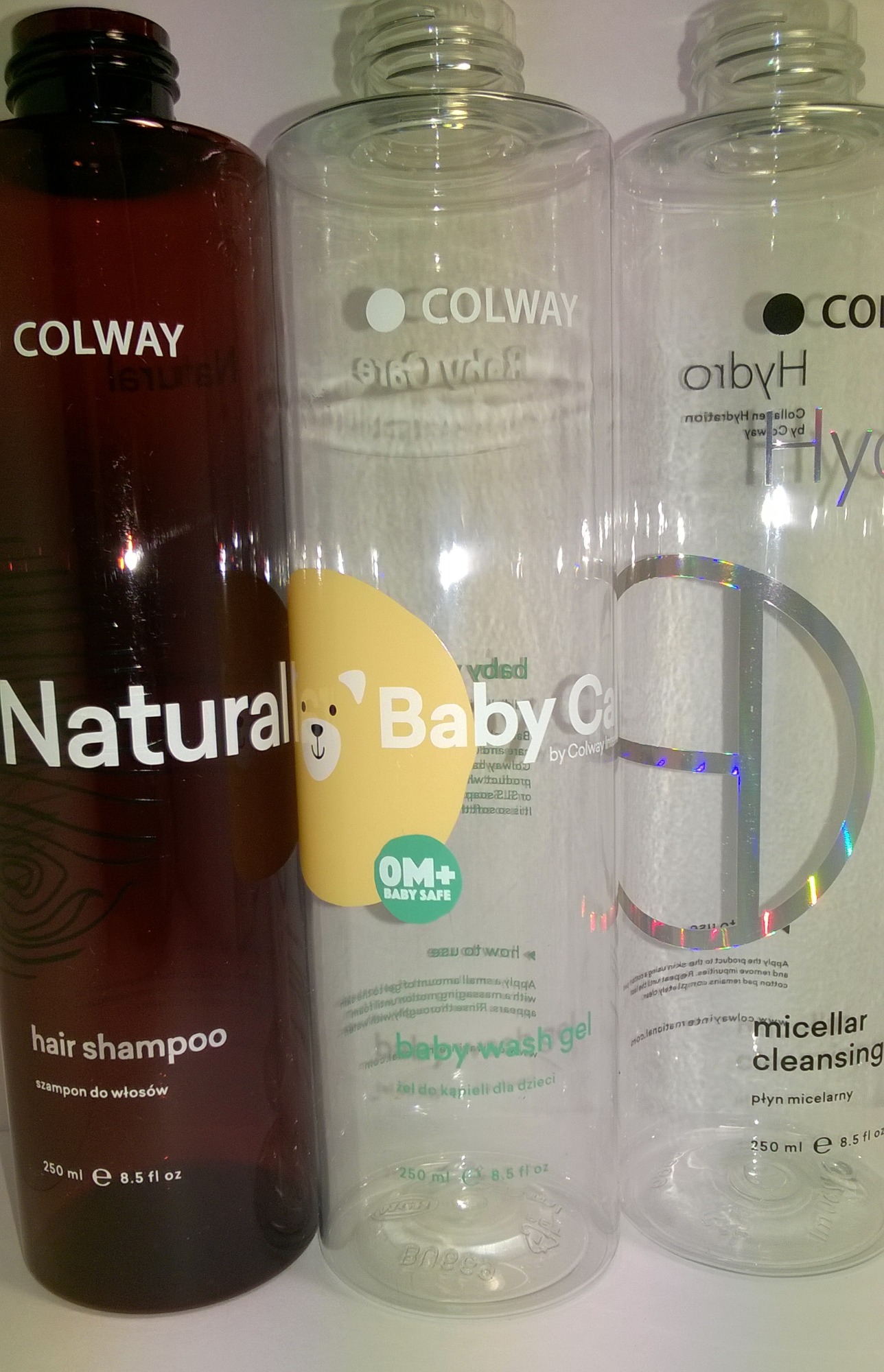 Trzy plastikowe butelki kosmetyków firmy Colway: brązowa z szamponem do włosów, przezroczysta z żelem do kąpieli dla dzieci i przezroczysta z płynem micelarnym, każda o pojemności 250 ml.
