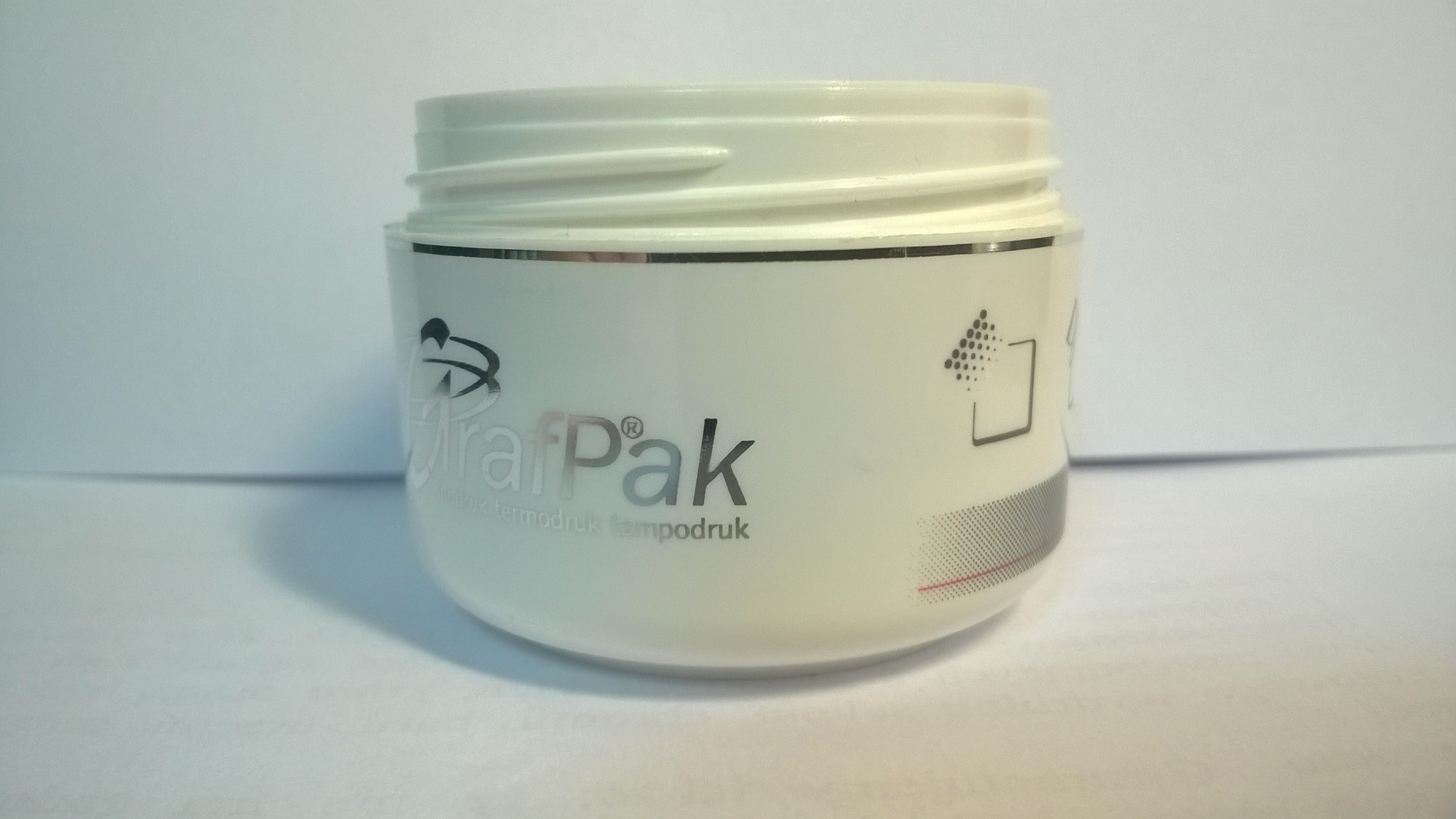 Biały pojemnik z nadrukowanym logo GrafPak oraz informacjami o termodruku i tampodruku na jasnym tle.