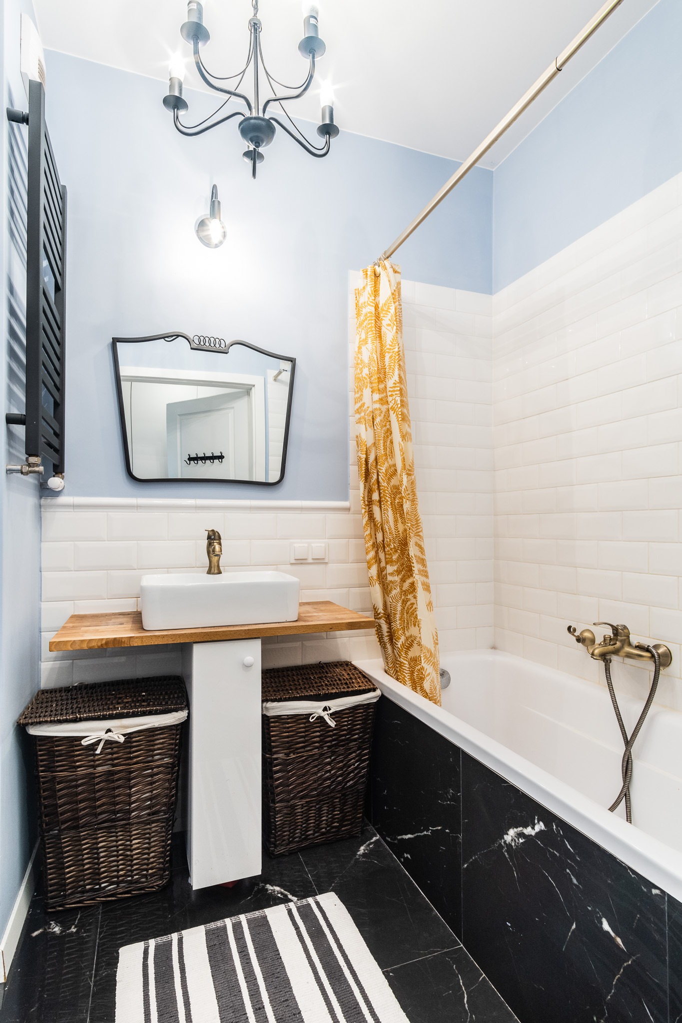 Nowoczesna łazienka z czarnymi marmurowymi płytkami podłogowymi i złotymi akcentami: bateria umywalkowa i zasłona prysznicowa w odcieniach złota.