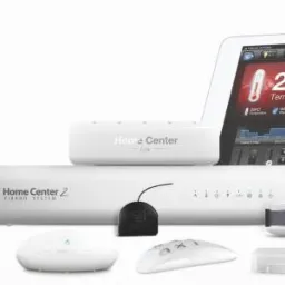 Zestaw urządzeń do inteligentnego domu Fibaro: centrala Home Center 2, Home Center Lite, czujniki, sterowniki i tablety z interfejsem użytkownika, prezentowane na białym tle.