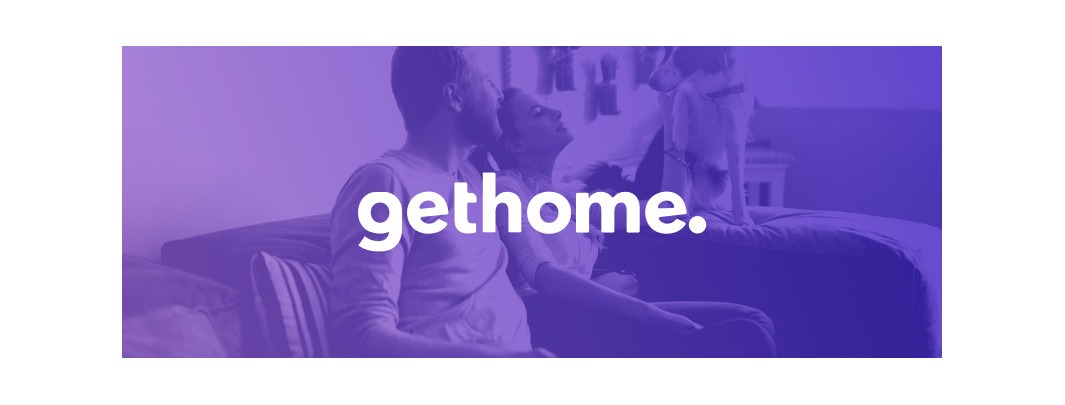 Para siedząca na kanapie z psem skaczącym w tle, logo 'gethome.'