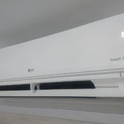 Biała jednostka klimatyzacji LG Smart Inverter zamontowana na ścianie, ustawiona na temperaturę 18 stopni Celsjusza.